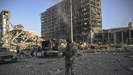 Un militaire ukrainien marche entre les débris du centre commercial Retroville et du quartier résidentiel après une attaque à Kiev, le 21 mars 2022. (ARIS MESSINIS / AFP)