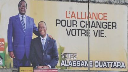 Affiche de campagne de l'alliance du RHDP photographiée le 21 novembre 2010 dans les rues d'Abidjan, la capitale ivoirienne. On y voit Henri Konan Bédié, le président du PDCI (debout) et Alassane Ouattara, l'actuel président ivoirien et leader du RDR. (SIA KAMBOU / AFP)