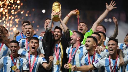 Lionel Messi porte la Coupe du Monde gagnée par l'équipe d'Argentine, lors de la finale de la Coupe du Monde de football 2022. (FRANCK FIFE / AFP)