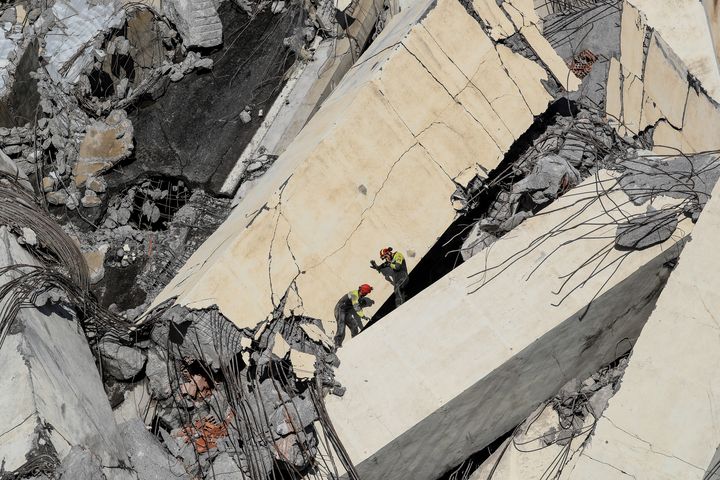 Des secouristes italiens recherchent des victimes dans les décombres du pont autoroutier de Gênes, en Italie, après son effondrement, le 14 août 2018. (VALERY HACHE / AFP)