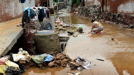 Une femme lave son linge dans un village &agrave; proximit&eacute; de P&eacute;kin, apr&egrave;s des inondations meurtri&egrave;res dans la capitale chinoise, le 24 juillet 2012. (LIU LIANMIN / AFP)