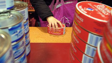 Une personne tient deux boites de harengs dans un centre de distribution des Restos du Coeur, le 30 novembre 2009 &agrave; Strasbourg. (FREDERICK FLORIN / AFP)