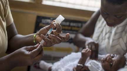 Un bébé est vacciné contre le paludisme par une infirmière à la maternité de la polyclinique Ewin à Cape Coast, au Ghana, le 30 avril 2019. (photo d'illustration) (CRISTINA ALDEHUELA / AFP)