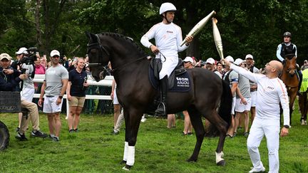 La flamme olympique transportée à cheval par le champion olympique Nicolas Touzaint, membre de l'équipe de France de concours complet), dans le Maine-et-Loire, le 28 mai 2024. (JOSSELIN CLAIR / MAXPPP)