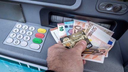 Un homme retire des billets à un distributeur automatique à Lille (Nord) le 4 janvier 2017. (Photo d'illustration) (PHILIPPE HUGUEN / AFP)