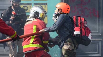 Un sapeur-pompier aux prises avec une manifestante en marge&nbsp;d'un défilé, à Paris, le 1er mai 2022. (ALAIN JOCARD / AFP)