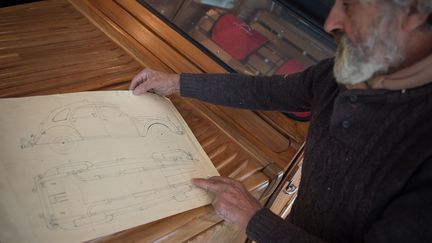 Michel Robillard montre les plans de son petit bijou. Il a déjà réalisé d'étonnantes maquettes à l'échelle 1/10, depuis la fin des années 90 :&nbsp;4 CV, Coccinelle Volkswagen de 1949, Auburn popularisée par l'acteur américain Clark Gable, Lincoln ou encore Bugatti Royale de 1936. (GUILLAUME SOUVANT / AFP)