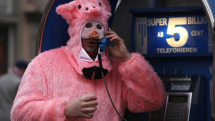 Un homme d&eacute;guis&eacute; en cochon passe un coup de t&eacute;l&eacute;phone en marge du d&eacute;fil&eacute; "Weiberfastnacht" au carnaval de Cologne (Allemagne), le 7 f&eacute;vrier 2013. (INA FASSBENDER / REUTERS)