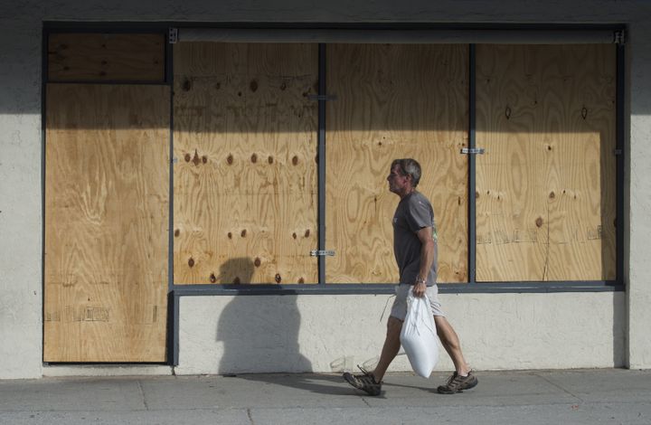 Un homme porte un sac de sable devant un magasin barricadé à&nbsp;Wrightsville Beach, en Caroline du Nord, aux Etats-Unis, le 11 septembre 2018.&nbsp; (ANDREW CABALLERO-REYNOLDS / AFP)