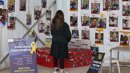 A woman meditates in front of portraits of Hamas hostages, February 12, 2024, in Tel Aviv, Israel.  (AHMAD GHARABLI / AFP)