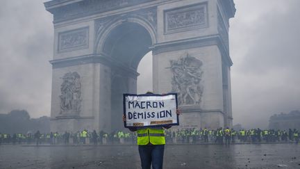 Un "gilet jaune" tient une pancarte appelant à la démission d'Emmanuel Macron, lors de la manifestation à Paris, le 1er décembre 2018. (CHRISTOPHE PETIT TESSON / MAXPPP)