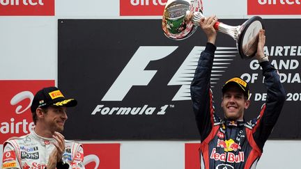 Sebastian Vettel (&agrave; droite) c&eacute;l&egrave;bre sa victoire au Grand prix de Buddh en Inde, aux c&ocirc;t&eacute;s de Jenson Button arriv&eacute; second, le 30 octobre 2011. (MANAN VATSYAYANA / AFP)