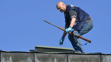 Un officier de police saisit une arme sur le toit depuis lequel un sniper a tir&eacute; sur la foule, &agrave; Hyvinkaa (Finlande), samedi 26 mai 2012. (JUSSI NUKARI / LEHTIKUVA /AFP)