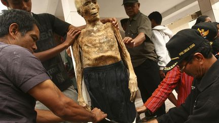 Des hommes habillent une momie &agrave; Toraja (Indon&eacute;sie), le 23 ao&ucirc;t 2012. Chaque ann&eacute;e, les familles enfilent des habits neufs &agrave; leurs anc&ecirc;tres momifi&eacute;s. (REUTERS)