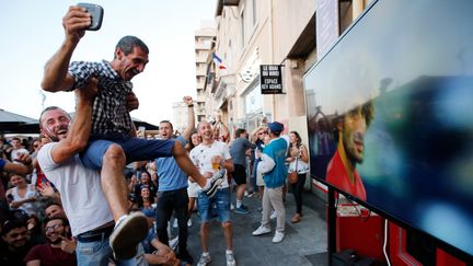 Un supporter est brandi par un autre homme après le but décisif de Samule Umtiti, le 10 juillet 2018, à Marseille (Bouches-du-Rhône). (JEAN-PAUL PELISSIER / REUTERS)