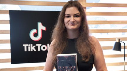 L'autrice allemande Sarah Prinz pose avec son livre, le best-seller "Dunbridge Academy", le 21 octobre à la Foire du Livre de Francfort (Allemagne). (ANDRE PAIN / AFP)