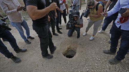 Des policiers et journalistes rassemblés autour du trou par lequel les détenus palestiniens se sont évadés de la prison de Gilboa (Israël), le 6 septembre 2021. (JALAA MAREY / AFP)