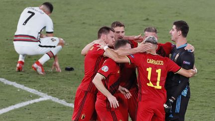 La joie et la peine. À côté des Belges qui célèbrent leur qualification en quart de finale aux dépens du Portugal (1-0), le 27 juin 2021, Cristiano Ronaldo est prostré au sol. Le capitaine de la Seleçao sait qu'il vient sans doute de jouer son dernier match dans un championnat d'Europe. (JOSE MANUEL VIDAL / AFP)