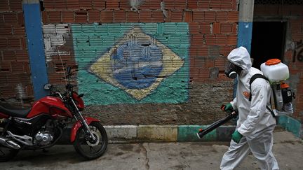 Un homme désinfecte la rue dans une favela à Rio de Janeiro, au Brésil, le 18 avril 2020. (CARL DE SOUZA / AFP)