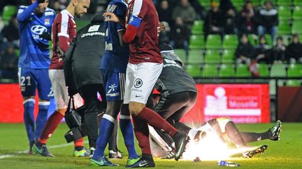 Le gardien lyonnais Anthony Lopes, étendu sur le sol, reçoit un pétard en provenance d'une tribune messine, samedi 3 décembre.&nbsp; (JEAN-CHRISTOPHE VERHAEGEN / AFP)