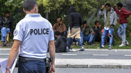 Un officier de police devant des migrants près de Calais, en Août 2017.&nbsp; (PHILIPPE HUGUEN / AFP)