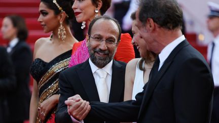 Le réalisateur iranien&nbsp;Asghar Farhadi, membre du jury, serrant amicalement la main du président Vincent Lindon. Signe qu'ils travailleront main dans la main pour départager les films en compétition. (VALERY HACHE / AFP)
