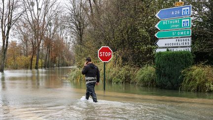 Un habitant de Neuville-sous-Montreuil (Pas-de-Calais) marche dans une rue inondée, le 13 novembre 2023. (DENIS CHARLET / AFP)