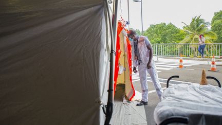 Un&nbsp;soignant&nbsp;regarde à l'intérieur d'une tente destinée aux&nbsp;patients Covid-19 au CHU Pierre Zobda-Quitman de Fort-de-France, le 30 juillet 2021. (LIONEL CHAMOISEAU / AFP)