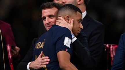 Emmanuel Macron tente de consoler Kylian Mbappé, après la défaite de l'équipe de France contre l'Argentine en finale de la Coupe du monde, le 18 décembre 2022 à Doha (Qatar). (KIRILL KUDRYAVTSEV / AFP)