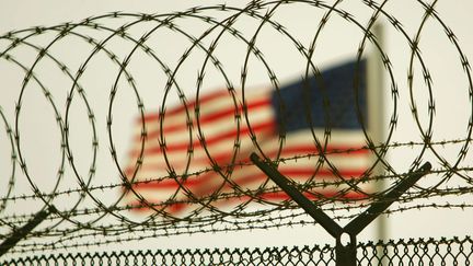 Un drapeau am&eacute;ricain flotte derri&egrave;re des barbel&eacute;s sur la base de Guantanamo, &agrave; Cuba, le 26 juin 2006. (BRENNAN LINSLEY / AP / SIPA)