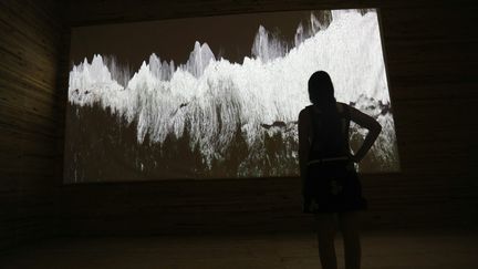 Prisca Meslier, cofondatrice de la Biennale d'art contemporain à Ajaccio, observe un écran sur lequel on peut voir l'œuvre "La Mer" de l'artiste Ange Leccia, le 21 juin 2022 à Bonifacio (PASCAL POCHARD-CASABIANCA / AFP)