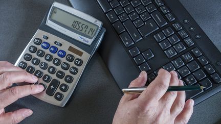 Un comptable en train de travailler sur son ordinateur avec l'aide d'une calculatrice. (JEAN-MARC QUINET / MAXPPP)