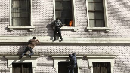 Des manifestants tentent d'escalader un immeuble en feu afin de l'&eacute;teindre au Caire (Egypte), le 3 f&eacute;vrier 2012. (ASMAA WAGUIH / REUTERS)