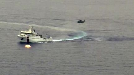 Des bateaux et un h&eacute;licopt&egrave;re des gardes-c&ocirc;tes italiens cherchant des survivants du naufrage d'un chalutier remplis de centaines de migrants, le 19 avril 2015 au large des c&ocirc;t&eacute;s italiennes. (GUARDIA COSTIERA / AFP)