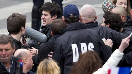 Une équipe du Petit Journal de Canal + est évacuée par le service d'ordre du Front national après avoir été agressée par de militants frontistes le 1er mai 2015 à Paris, lors d'une manifestation du parti. (KENZO TRIBOUILLARD / AFP)