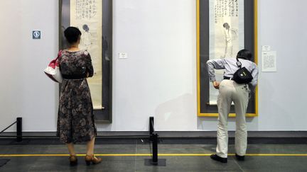 Des visiteurs face aux peintures de Wang Mengbai (gauche) et Qi Baishi, à l'occasion d'une ecposition consacrée aux maîtres de la peinture chinoise à Guangzhou, en mars 2014.
 (LIANG XU / XINHUA)