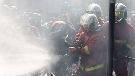 Une manifestante tente d'empêcher les pompiers d'éteindre un incendie après des affrontements lors de la manifestation du 1er-Mai (fête du travail), sur la place de la République, à Paris, en France, le 1er mai 2022. (MYLENE DEROCHE / MAXPPP)