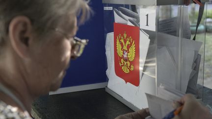 Une membre de commission électorale examine un passeport dans un bureau de vote mobile, le 6 septembre 2023, lors d'une soi-disant élection organisée par les autorités prorusses de Donetsk (Ukraine). (STRINGER / AFP)