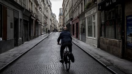 Un homme circule à vélo dans une rue de Paris. Photo d'illustration. (PHILIPPE LOPEZ / AFP)