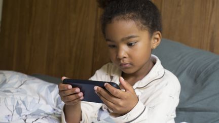 Une petite fille sur son téléphone portable. (ANNE-SOPHIE BOST / MAXPPP)