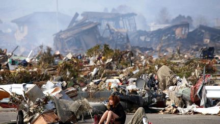 Une femme pleure parmi les d&eacute;combres &agrave; Natori (Japon) apr&egrave;s le passage du tsunami, le 13 mars 2011. (ASAHI SHIMBUN / REUTERS)