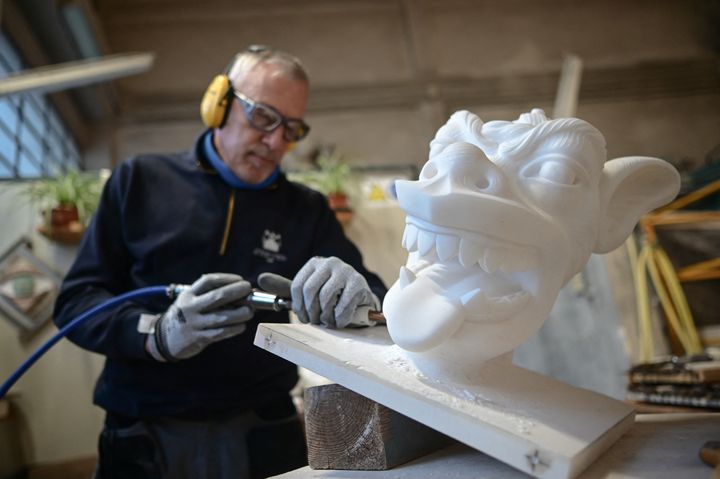 Antonino Cagnina cisèle avec un marteau pneumatique une gargouille Doccione à Cantiere Marmisti, la marbrerie où le marbre de la carrière de Candoglia est transformé en pierres de taille, éléments architecturaux et ornementaux, sculptures et statues de la cathédrale du Dôme de Milan, le 11 décembre 2024, à Milan (Italie). (PIERO CRUCIATTI / AFP)