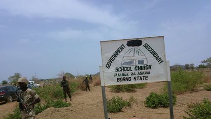 Des soldats aux côtés d'un panneau du lycée Chibok au Nigéria, le 21 avril 2014. (HARUNA UMAR/AP/SIPA)