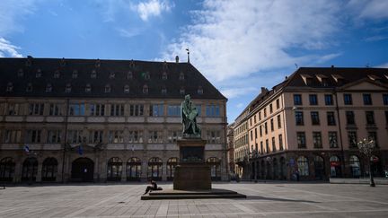 Sur cette place de Strasbourg (Bas-Rhin), il ne reste qu'un seul badaud assis sous la statue, le 17 mars 2020. (PATRICK HERTZOG / AFP)