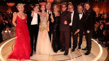 Christopher Nolan, réalisateur du film "Oppenheimer", entouré de Florence Pugh, Cillian Murphy, Emily Blunt, Emma Thomas, Robert Downey Jr, Charles Roven, Matt Damon et Ludwig Göransson lors de la cérémonie des Golden Globes, à Los Angeles, le 8 janvier 2024. (CHRISTOPHER POLK / GOLDEN GLOBES / AFP)