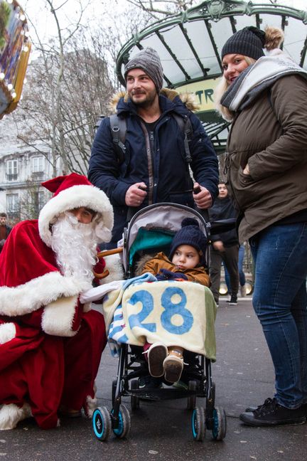 Raphaël Godet, père Noël d'un jour, pose avec une famille à la sortie du métro Abbesses, à Paris, le 20&nbsp;décembre&nbsp;2017. (ELODIE DROUARD / FRANCEINFO)