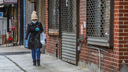 Une femme avec un masque de protection marche dans le quartier de&nbsp;Manhattan, à New York, le 28 mars 2020. (VANESSA CARVALHO / BRAZIL PHOTO PRESS / AFP)