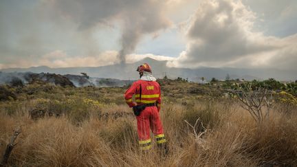 Un pompier face à un nuage de fumées provoqué par l'éruption du volcan Cumbre Vieja sur l'île de la Palma, aux Canaries (Espagne), le 21 septembre 2021. (ANDRES GUTIERREZ / ANADOLU AGENCY)