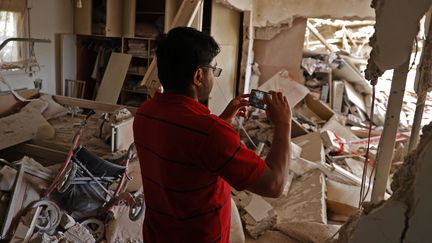 Un Israëlien prend en photo les dégâts d'une maison détruite par un tir de roquette du Hamas, à Ashkelon, près de Gaza, en Israël, mardi 11 mai 2021. (JACK GUEZ / AFP)