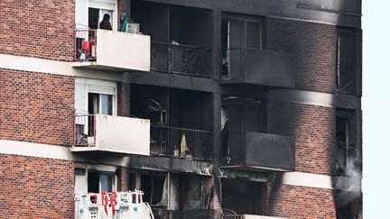 Des habitants au dernier étage de la tour incendiée dans la cité Maurice-Thorez sur L'Ile-Saint-Denis (Seine-Saint-Denis), le 19 août 2023. (STEFANO RELLANDINI / AFP)